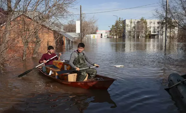Two men ride a boat delivering food in a flooded area in Orenburg, Russia, on Thursday, April 11, 2024. Russian officials are scrambling to help homeowners displaced by floods, as water levels have risen in the Ural River. The river's water level in the city of Orenburg was above 10 meters (33 feet) Wednesday, state news agency Ria Novosti reported, citing the regional governor. (AP Photo)
