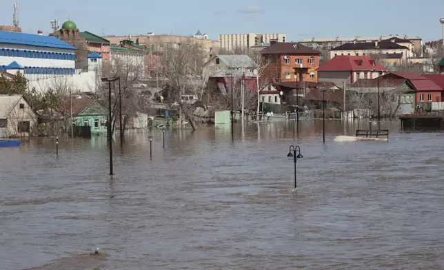 Local residents stand at barriers watching a flooded area in Orenburg, Russia, on Thursday, April 11, 2024. Russian officials are scrambling to help homeowners displaced by floods, as water levels have risen in the Ural River. The river's water level in the city of Orenburg was above 10 meters (33 feet) Wednesday, state news agency Ria Novosti reported, citing the regional governor. (AP Photo)
