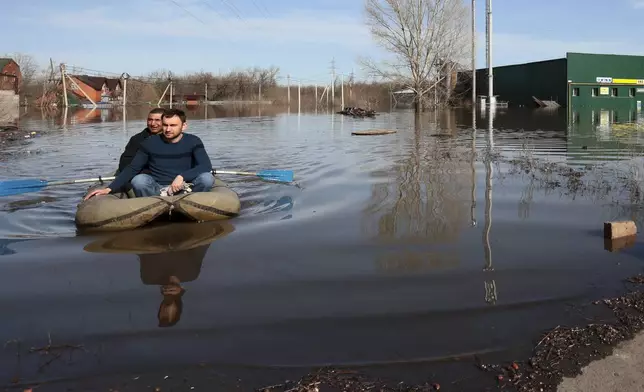 Two men ride a boat in a flooded area in Orenburg, Russia, on Thursday, April 11, 2024. Russian officials are scrambling to help homeowners displaced by floods, as water levels have risen in the Ural River. The river's water level in the city of Orenburg was above 10 meters (33 feet) Wednesday, state news agency Ria Novosti reported, citing the regional governor. (AP Photo)