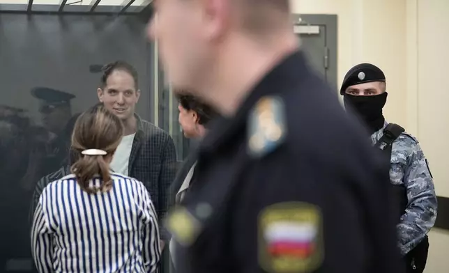 Wall Street Journal reporter Evan Gershkovich speaks with his lawyers standing in a glass cage in a courtroom at the First Appeals Court of General Jurisdiction in Moscow, Russia, Tuesday, April 23, 2024. A court will considers an appeal against the arrest of WSJ reporter Evan Gershkovich who was detained on espionage charges in Yekaterinburg last year. (AP Photo/Alexander Zemlianichenko)