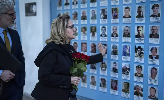 U.S. representative Madeleine Deane, D-Pa, places flowers at a memorial wall of Ukrainian soldiers killed during the war at Saint Michael cathedral in Kyiv, Ukraine, Monday, April 22, 2024. A bipartisan delegation of U.S. Congress members met President Volodymyr Zelenskyy in Kyiv on Monday and praised the historic House vote to approve $61 billion in military aid for Ukraine. (AP Photo/Francisco Seco)