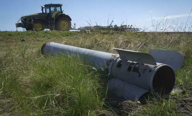 A fragment of a Russian missile is seen in the foreground as a farmer works on his field in Izium, Kharkiv region, Ukraine, Saturday, April 20, 2024. (AP Photo/Andrii Marienko)