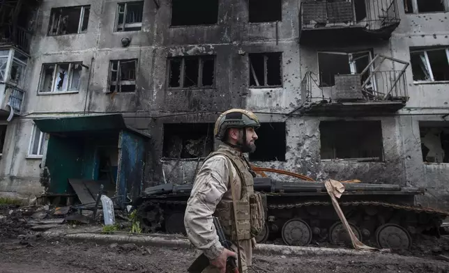 FILE - A Ukrainian soldier passes by a damaged apartment building in Chasiv Yar, the site of heavy battles with the Russian forces in the Donetsk region, Ukraine, Tuesday, May 9, 2023. (Iryna Rybakova via AP, File)