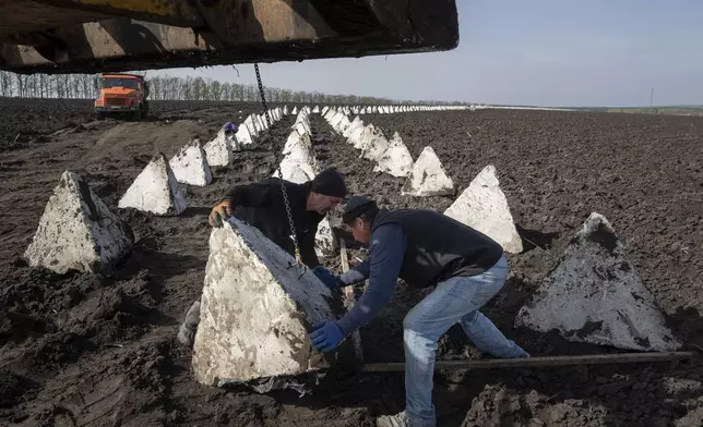 Workers install dragon teeth during the construction of new defensive positions close to the Russian border in Kharkiv region, Ukraine, on Wednesday, April 17, 2024. (AP Photo/Evgeniy Maloletka)