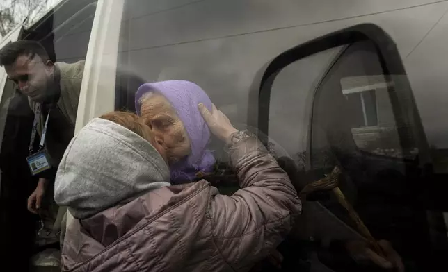 FILE - Olha Faichuk, 79, kisses her neighbor as she is evacuated from her home, which was heavily damaged by a Russian airstrike in Lukiantsi, Kharkiv region, Ukraine, on Tuesday, April 16, 2024. (AP Photo/Evgeniy Maloletka, File)