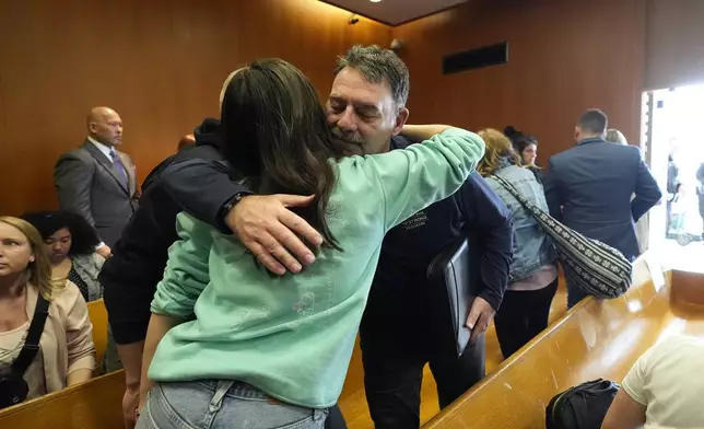 Buck Myre hugs Reina St. Juliana, Hana St. Juliana's sister, after the sentencing of James and Jennifer Crumbley, Tuesday, April 9, 2024, in Pontiac, Mich. The Crumbleys, the parents of a Michigan school shooter, were sentenced to at least 10 years in prison Tuesday for failing to take steps that could have prevented the killing of four students in 2021. (AP Photo/Carlos Osorio)