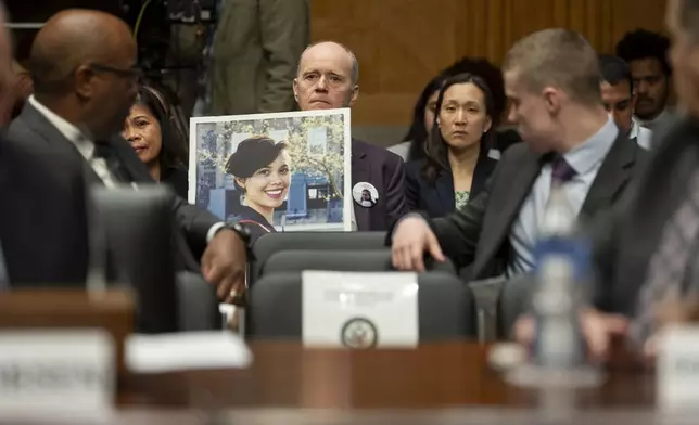 Chris Moore, center, holds a photo of his daughter Danielle Moore, who died in the March 2019 crash of Ethiopian Airlines flight 302, during a Senate Homeland Security and Governmental Affairs - Subcommittee on Investigations hearing to examine Boeing's broken safety culture on Wednesday, April 17, 2024, in Washington. (AP Photo/Kevin Wolf)