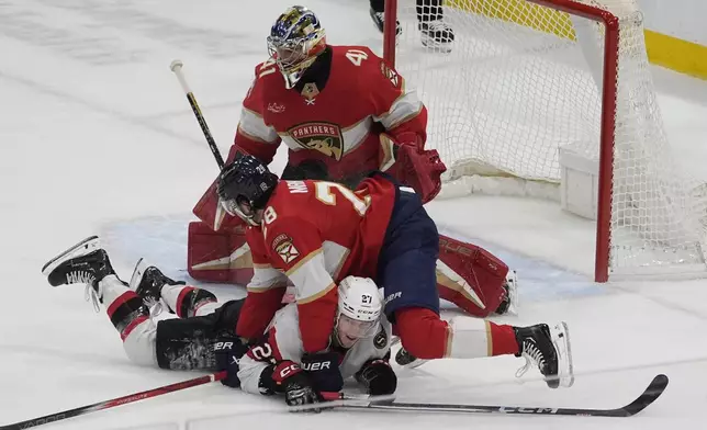 Florida Panthers defenseman Josh Mahura (28) falls on Ottawa Senators left wing Parker Kelly (27) after tripping him during the first period of an NHL hockey game, Tuesday, April 9, 2024, in Sunrise, Fla. (AP Photo/Marta Lavandier)