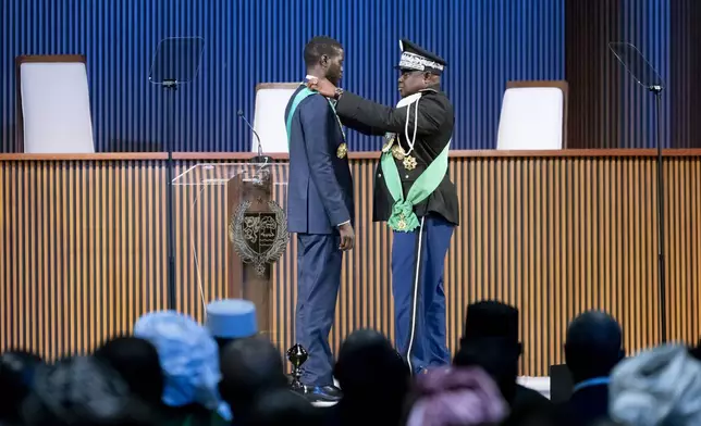 Bassirou Diomaye Faye, centre left, receives the Necklace of the Grand Master of the National Order of the Lion during his swearing in ceremony as Senegal's president in Dakar, Senegal, Tuesday, April 2, 2024. Senegal has sworn in Bassirou Diomaye Faye as its new president, completing the previously little-known opposition figure’s dramatic ascent from prison to the palace in recent weeks. Faye was released from prison less than two weeks before the March election following a political amnesty announced by the outgoing president. (AP Photo/Sylvain Cherkaoui)