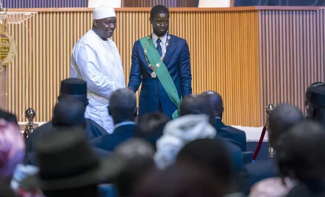Bassirou Diomaye Faye, right, greets Gambia's President Adama Barrow during his swearing in ceremony as Senegal's president in Dakar, Senegal, Tuesday, April 2, 2024. Senegal has sworn in Bassirou Diomaye Faye as its new president, completing the previously little-known opposition figure’s dramatic ascent from prison to the palace in recent weeks. Faye was released from prison less than two weeks before the March election following a political amnesty announced by the outgoing president. (AP Photo/Sylvain Cherkaoui)