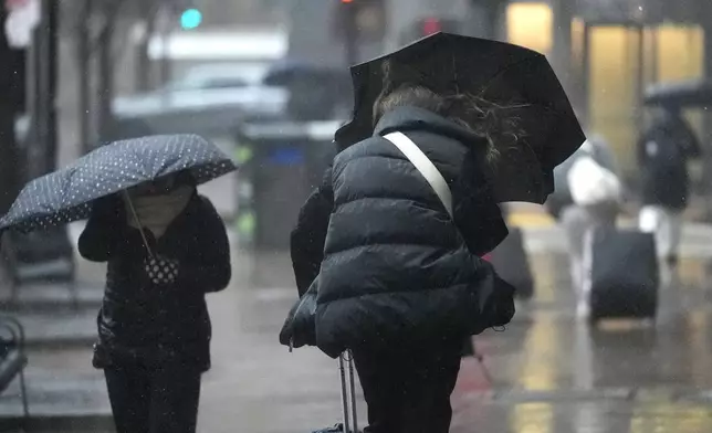 Commuters walk with umbrellas through wind-driven rain near South Station, Thursday, April 4, 2024, in Boston. (AP Photo/Charles Krupa)