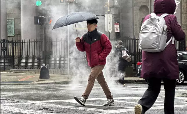 A pedestrian walks through downtown Boston during a rain storm, Wednesday, April 3, 2024. A nor'easter has brought heavy wind, rain and snow to New England. (AP Photo/Robert F. Bukaty)