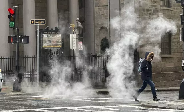 A pedestrian walks through downtown Boston during a rain storm, Wednesday, April 3, 2024. A nor'easter has brought heavy wind, rain and snow to New England. (AP Photo/Robert F. Bukaty)