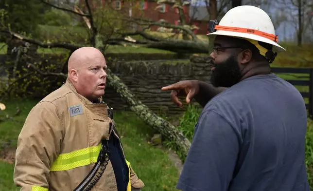 Capt. Patrick Staudenheimer, left, with the Anchorage Middletown Fire Department, speaks with an employee of the Louisville Gas and Electric company informing him of possible gas leaks following severe storms in Prospect, Ky., Tuesday, April 2, 2024. (AP Photo/Timothy D. Easley)