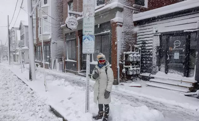 Emma Pidden waits for her bus on Congress Street in Portland, Maine, Thursday, April 4, 2024, following a spring snowstorm. Pidden said she decided to take the bus into her office because she was worried about losing WiFi at home. (Brianna Soukup/Portland Press Herald via AP)