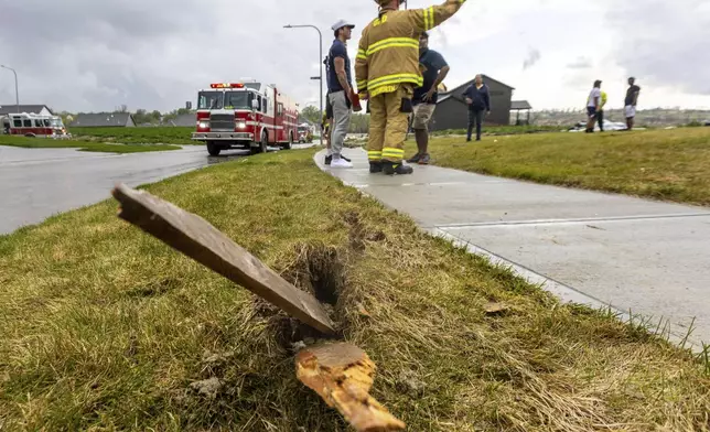 A piece of wood is embedded in the ground as firefighters assess the damages to houses after a tornado passed through the area near Omaha, Neb., on Friday, April 26, 2024. (Chris Machian/Omaha World-Herald via AP)