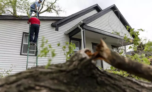 Robert Keesee helps his father, Randy Keesee, up a ladder to access roof damage to their home after a severe storm hit the neighborhood in Council Bluffs, Iowa, on Friday, April 26, 2024. (Anna Reed/Omaha World-Herald via AP)