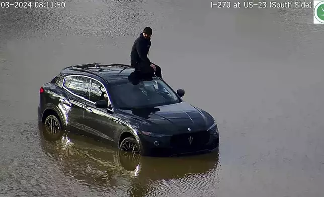 In this image released by the Ohio Department of Transportation, a person is seen stranded on his vehicle in flood waters at I-270 and US 23 in Columbus' South Side, Ohio, Tuesday, April 3, 2024. Authorities said the driver drove around barricades on Wednesday morning around 8 a.m and stranded in high water. The barricades were placed since Tuesday afternoon as water from the Scioto River continued to rise due to heavy rainall in the region. (Ohio Department of Transportation via AP)