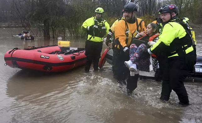 Beaver Falls, Pa., firefighter Jason Tyger, right, gets some help carrying a woman from a boat after she was rescued from her flooded home on McKim Way in Franklin Township, Pa., Wednesday, April 3, 2024. (Lucy Schaly/Pittsburgh Post-Gazette via AP)