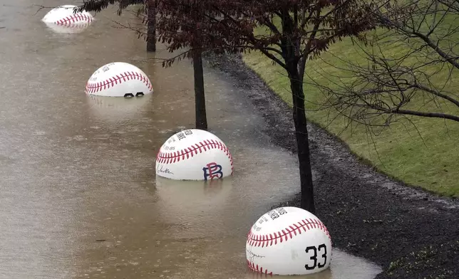 A display of giant baseballs lining the Northshore riverwalk outside PNC Park in Pittsburgh are partially submerged by the overflowing Allegheny River Wednesday, April 3, 2024. (AP Photo/Gene J. Puskar)