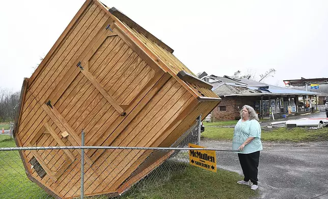 Jamie Coleman looks over at her storage building, Wednesday, April 3, 2024, that blew over in her yard along Route 60 in Hico, W.Va., during a storm that hit the area the day before. (Rick Barbero/The Register-Herald via AP)