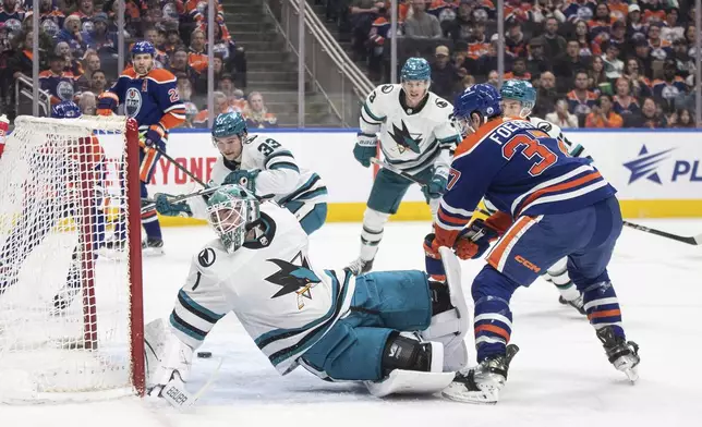 San Jose Sharks goalie Devin Cooley (1) is scored against by Edmonton Oilers' Warren Foegele (37) during second-period NHL hockey game action in Edmonton, Alberta, Monday, April 15, 2024. (Jason Franson/The Canadian Press via AP)