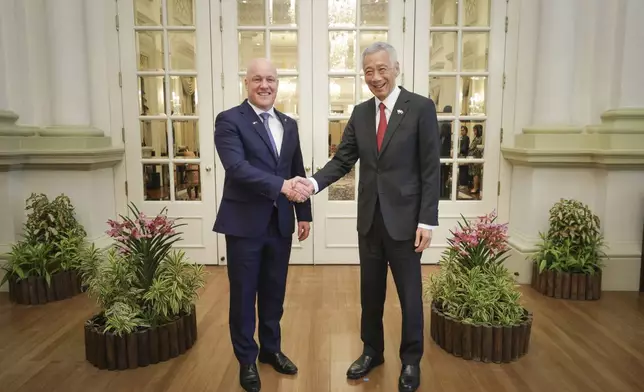 In this photo released by Singapore's Ministry of Communications and Information, New Zealand Prime Minister Luxon, left, shakes hands with Singapore's Prime Minister Lee Hsien Loong at the Istana, Monday, April 15, 2024. (Terence Tan/Ministry of Communications and Information via AP)