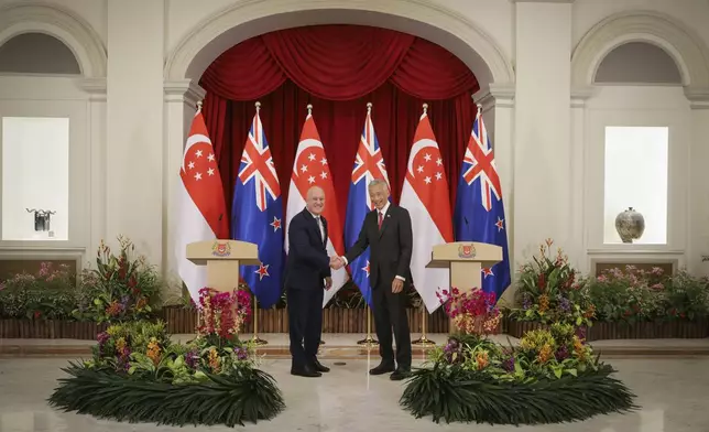 In this photo released by Singapore's Ministry of Communications and Information, New Zealand Prime Minister Luxon, left, shakes hands with Singapore's Prime Minister Lee Hsien Loong at the Istana, Monday, April 15, 2024. (Terence Tan/Ministry of Communications and Information via AP)