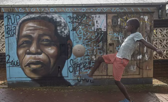 A child kicks a football in front of a mural of Nelson Mandela, in Soweto, South Africa, as the country celebrates Freedom Day. Saturday, April 27, 2024.The day marks April 27 when the country held pivotal first democratic election in 1994 that announced the official end of the racial segregation and oppression of apartheid. (AP Photo)