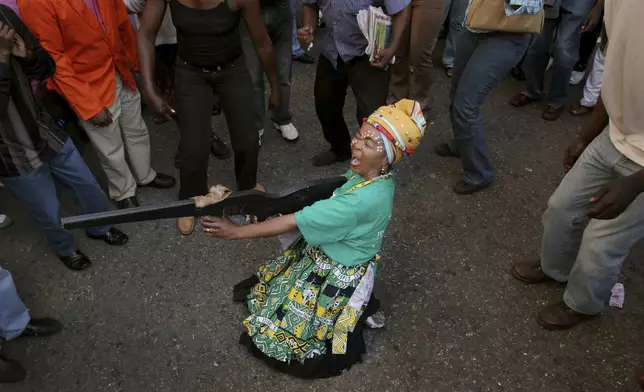 FILE — A woman pretending to fire a mock weapon joins supporters of former deputy president Jacob Zuma in protest outside the High Court in Johannesburg, Wednesday, April 5, 2006 during Zuma's rape trial. For the first time since 1994, the ruling African National Congress (ANC) might receive less than 50% of votes after Zuma stepped down in disgrace in 2018 amid a swirl of corruption allegations and has given his support to the newly-formed UMkhonto WeSiizwe political party. (AP Photo/Denis Farrell/File)