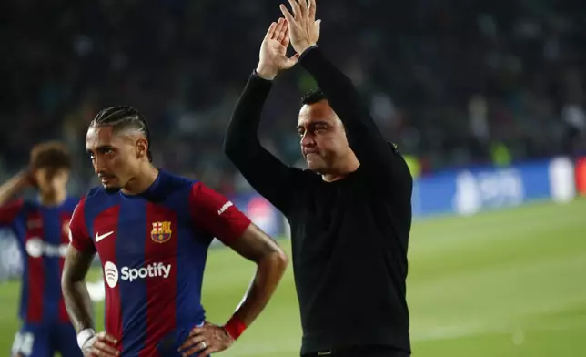 Barcelona's head coach Xavi Hernandez, right, and Barcelona's Raphinha salute supporters at the end of the Champions League quarterfinal second leg soccer match between Barcelona and Paris Saint-Germain at the Olimpic Lluis Companys stadium in Barcelona, Spain, Tuesday, April 16, 2024. (AP Photo/Joan Monfort)