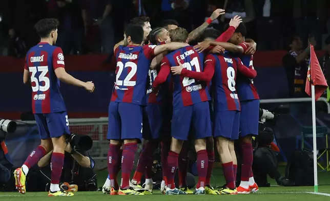 Barcelona's Raphinha celebrates with teammates after scoring the opening goal during the Champions League quarterfinal second leg soccer match between Barcelona and Paris Saint-Germain at the Olimpic Lluis Companys stadium in Barcelona, Spain, Tuesday, April 16, 2024. (AP Photo/Joan Monfort)