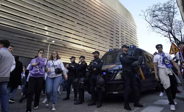 Police officers stand guard outside the Santiago Bernabeu stadium, ahead of the Champions League quarterfinal first leg soccer match between Real Madrid and Manchester City in Madrid, Spain, Tuesday, April 9, 2024. This week's Champions League soccer games will go ahead as scheduled despite an Islamic State terror threat. A media outlet linked to the terror group has issued multiple posts calling for attacks at the stadiums hosting quarterfinal matches in Paris, Madrid and London. (AP Photo/Andrea Comas)