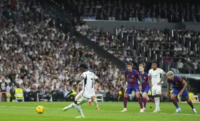 Real Madrid's Vinicius Junior scores on a penalty kick his side's opening goal during the Spanish La Liga soccer match between Real Madrid and Barcelona at the Santiago Bernabeu stadium in Madrid, Spain, Sunday, April 21, 2024. (AP Photo/Manu Fernandez)