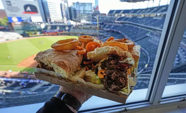 A Four Bagger hamburger is shown at Truist Park before a baseball game between the Texas Rangers and the Atlanta Braves Sunday, April 21, 2024, in Atlanta. The culinary game at MLB ballparks has exploded in the past 20 years. Eating healthy is a challenge. (AP Photo/John Bazemore)