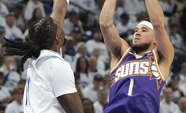 Phoenix Suns guard Devin Booker (1) shoots over Minnesota Timberwolves center Naz Reid during the first half of Game 1 of an NBA basketball first-round playoff series, Saturday, April 20, 2024, in Minneapolis. (AP Photo/Abbie Parr)