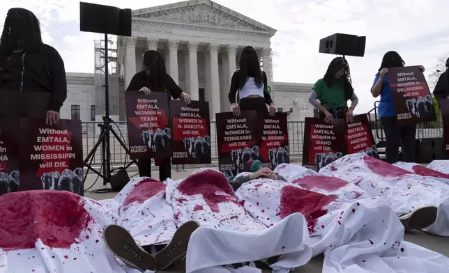 Abortion rights activists, covered in blankets with red paint, lie down as they rally outside the Supreme Court, Wednesday, April 24, 2024, in Washington. (AP Photo/Jose Luis Magana)