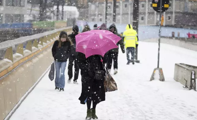 Pedestrians make their way through the snowy weather in Stockholm, Sweden April 2, 2024. Winter is not yet over in southern Sweden, spring took a break after a few Easter days with higher temperatures. (Anders Wiklund/TT via AP)