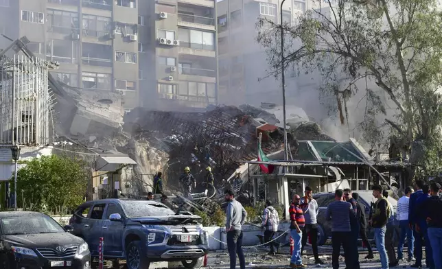 In this photo released by the official Syrian state news agency SANA, people gather near a destroyed building struck by Israeli jets in Damascus, Syria, Monday, April 1, 2024. An Israeli airstrike has destroyed the consular section of Iran's embassy in Syria, killing a senior Iranian military adviser and roughly a handful of other people, Syrian state media said Monday. (SANA via AP)