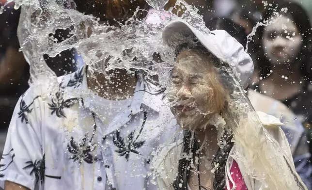 A couple react as a bucket of water is splashed on them during the Songkran water festival to celebrate the Thai New Year in Prachinburi Province, Thailand, Saturday April 13, 2024. It's the time of year when many Southeast Asian countries hold nationwide water festivals to beat the seasonal heat, as celebrants splash friends, family and strangers alike in often raucous celebration to mark the traditional Theravada Buddhist New Year. (AP Photo/Wason Wanichakorn)