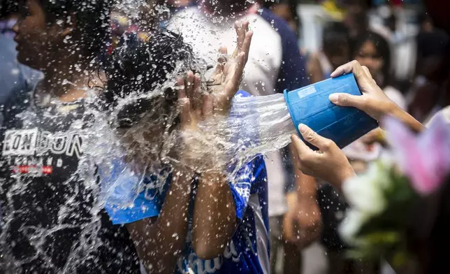 A man reacts as a bucket of water is splashed on him during the Songkran water festival to celebrate the Thai New Year in Prachinburi Province, Thailand, Saturday April 13, 2024. It's the time of year when many Southeast Asian countries hold nationwide water festivals to beat the seasonal heat, as celebrants splash friends, family and strangers alike in often raucous celebration to mark the traditional Theravada Buddhist New Year. (AP Photo/Wason Wanichakorn)