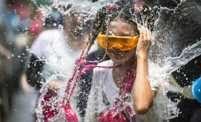 A woman reacts as a bucket of water is splashed on her during the Songkran water festival to celebrate the Thai New Year in Prachinburi Province, Thailand, Saturday April 13, 2024. It's the time of year when many Southeast Asian countries hold nationwide water festivals to beat the seasonal heat, as celebrants splash friends, family and strangers alike in often raucous celebration to mark the traditional Theravada Buddhist New Year. (AP Photo/Wason Wanichakorn)