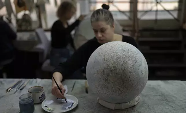 An artist paints a globe at a studio in London, Tuesday, Feb. 27, 2024. Globes in the age of Google Earth capture the imagination and serve as snapshots of how the owners see the world and their place in it. Peter Bellerby made his first globe for his father, after he could not find one accurate or attractive enough. In 2008, he founded Bellerby &amp; Co. Globemakers in London. His team of dozens of artists and cartographers has made thousands of bespoke globes up to 50 inches in diameter. The most ornate can cost six figures. (AP Photo/Kin Cheung)