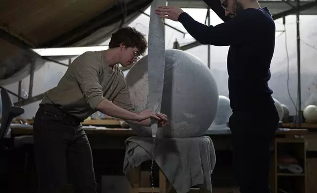 Artists make a globe at a studio in London, Tuesday, Feb. 27, 2024. Globes in the age of Google Earth capture the imagination and serve as snapshots of how the owners see the world and their place in it. Peter Bellerby made his first globe for his father, after he could not find one accurate or attractive enough. In 2008, he founded Bellerby &amp; Co. Globemakers in London. His team of dozens of artists and cartographers has made thousands of bespoke globes up to 50 inches in diameter. The most ornate can cost six figures. (AP Photo/Kin Cheung)