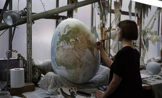 An artist paints a globe at a studio in London, Tuesday, Feb. 27, 2024. Globes in the age of Google Earth capture the imagination and serve as snapshots of how the owners see the world and their place in it. Peter Bellerby made his first globe for his father, after he could not find one accurate or attractive enough. In 2008, he founded Bellerby &amp; Co. Globemakers in London. His team of dozens of artists and cartographers has made thousands of bespoke globes up to 50 inches in diameter. The most ornate can cost six figures. (AP Photo/Kin Cheung)