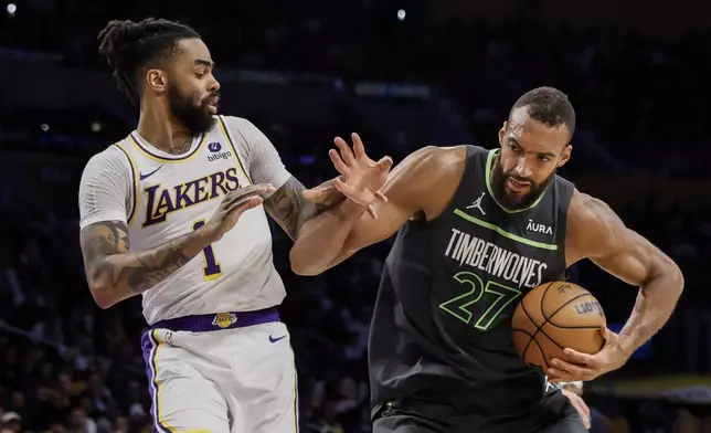 Minnesota Timberwolves center Rudy Gobert (27) dribbles past Los Angeles Lakers guard D'Angelo Russell (1) during the first half of an NBA basketball game, Sunday, April 7, 2024, in Los Angeles. (AP Photo/Etienne Laurent)
