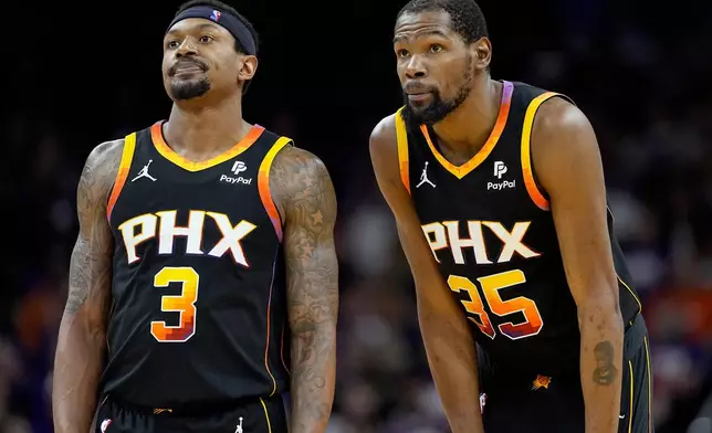 Phoenix Suns guard Bradley Beal (3) and forward Kevin Durant watch a free throw during the second half of Game 3 of an NBA basketball first-round playoff series against the Minnesota Timberwolves, Friday, April 26, 2024, in Phoenix. (AP Photo/Matt York)