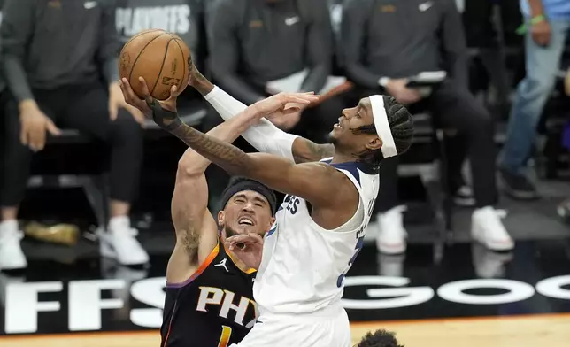 Minnesota Timberwolves forward Jaden McDaniels, right, drives past Phoenix Suns guard Devin Booker during the first half of Game 4 of an NBA basketball first-round playoff series, Sunday, April 28, 2024, in Phoenix. (AP Photo/Ross D. Franklin)