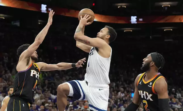 Minnesota Timberwolves forward Kyle Anderson, center, gets past Phoenix Suns forward Josh Okogie and Suns guard Devin Booker for a shot during the first half of Game 4 of an NBA basketball first-round playoff series, Sunday, April 28, 2024, in Phoenix. (AP Photo/Ross D. Franklin)