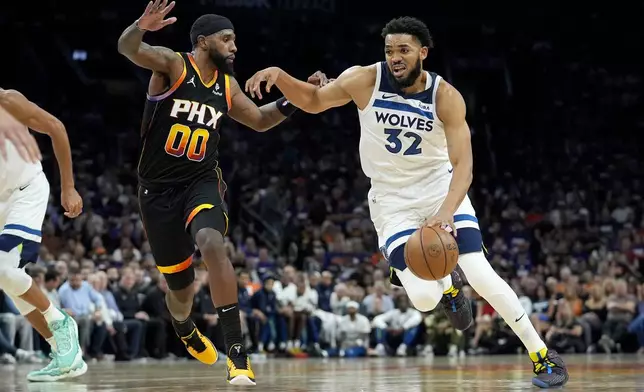 Minnesota Timberwolves center Karl-Anthony Towns (32) drives on Phoenix Suns forward Royce O'Neale during the first half of Game 3 of an NBA basketball first-round playoff series, Friday, April 26, 2024, in Phoenix. (AP Photo/Matt York)